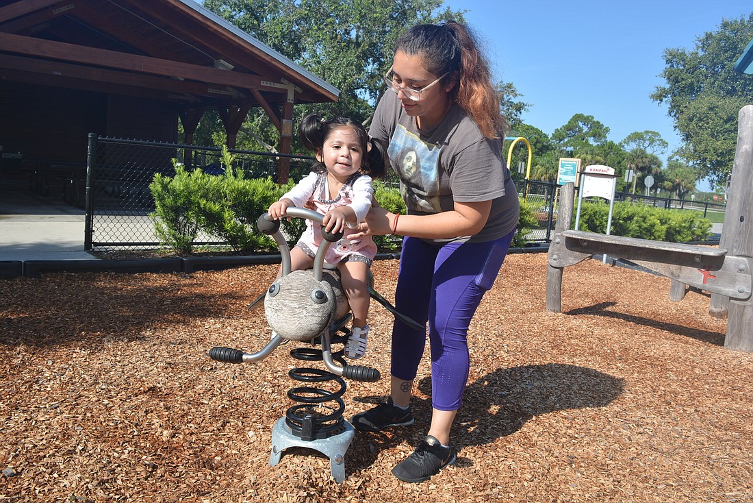 One-year-old Venus Gonzalez gets some help from her mom, Cenya Moreno, at Tom Bennett Park. The pair have fun, despite the heat. Manatee County plans to add shade to the playground area next year.