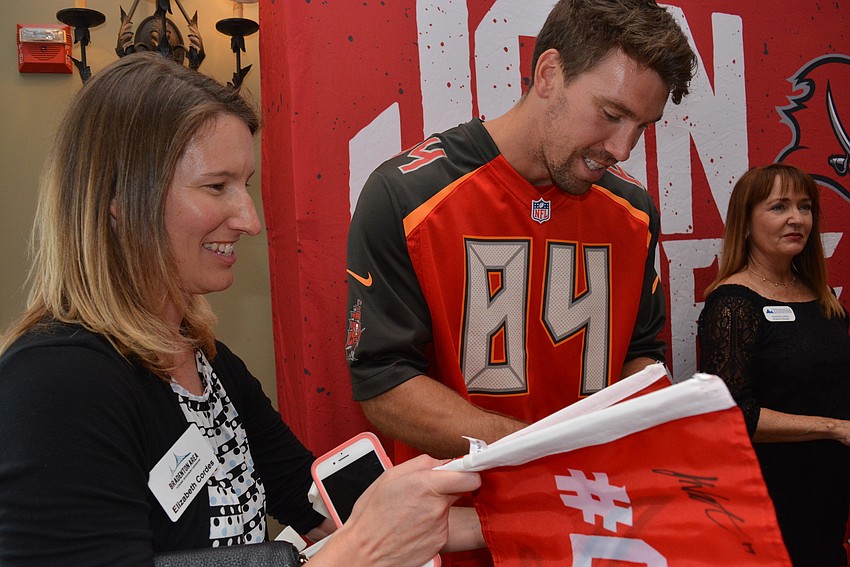 Parrish's Elizabeth Cordes, of the Bradenton Area Economic Development Corp. has Bucs' tight end Cameron Brate autograph two flags for her children, Parker and Deagan.