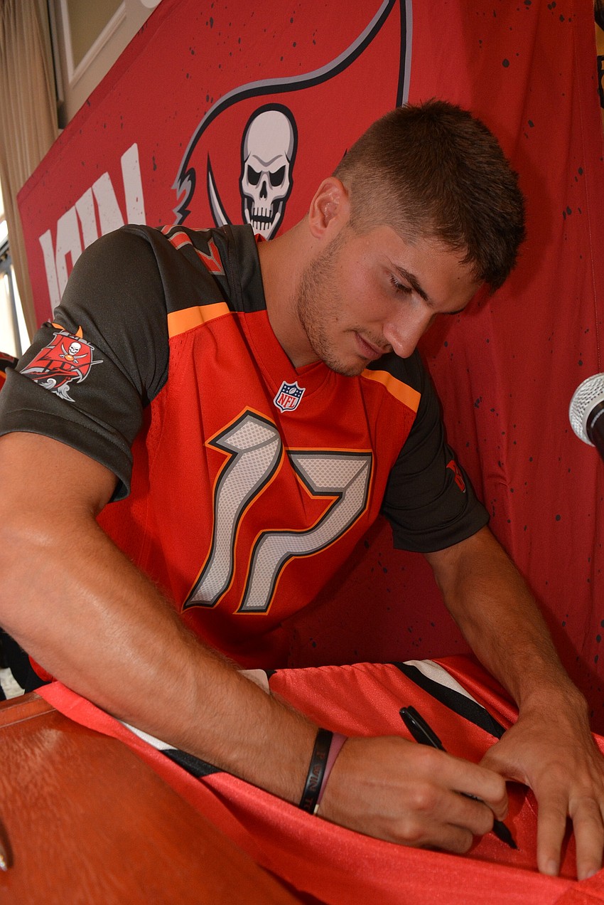 Bucs' wide receiver Justin Watson autographs a flag for an attendee.