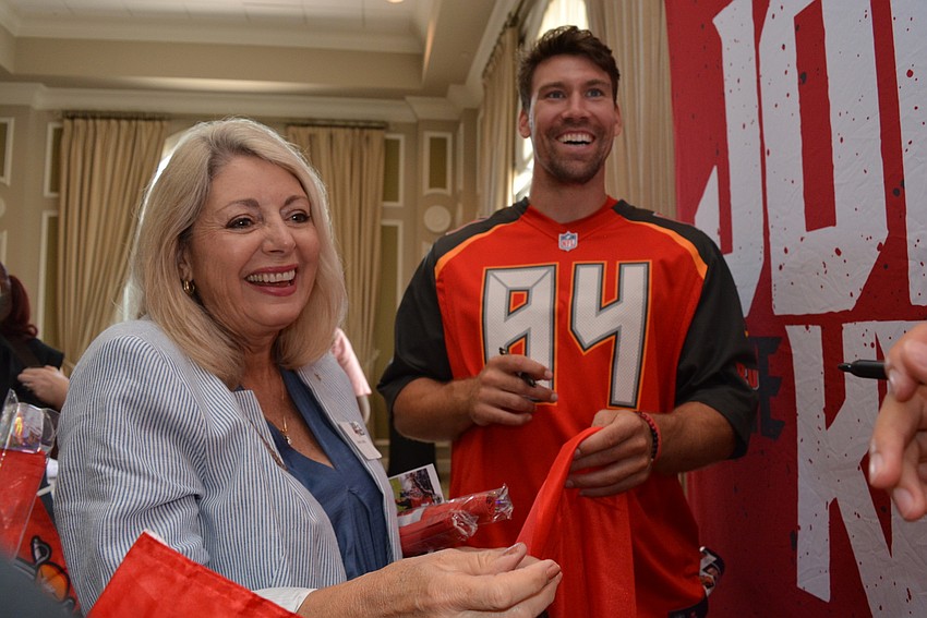 Ameriprise Financial's Sandra Cutcliffe has  tight end Cameron Brate and wide receiver Justin Watson, not pictured, autograph flags she takes back to the office.