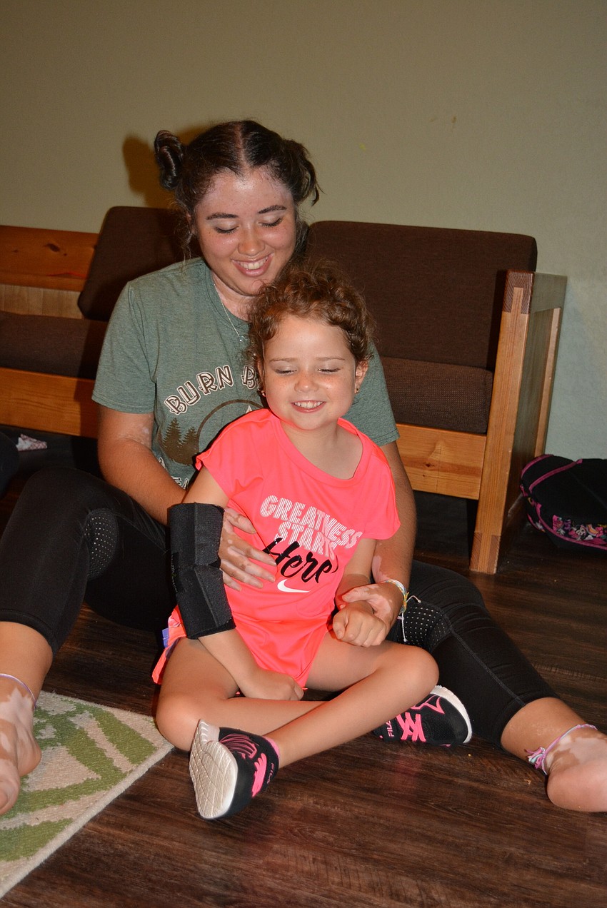 Counselor and Lakewood Ranch High School student Gabby Vazquez,  supports Ema Offner as she the pair do yoga inside a cabin.