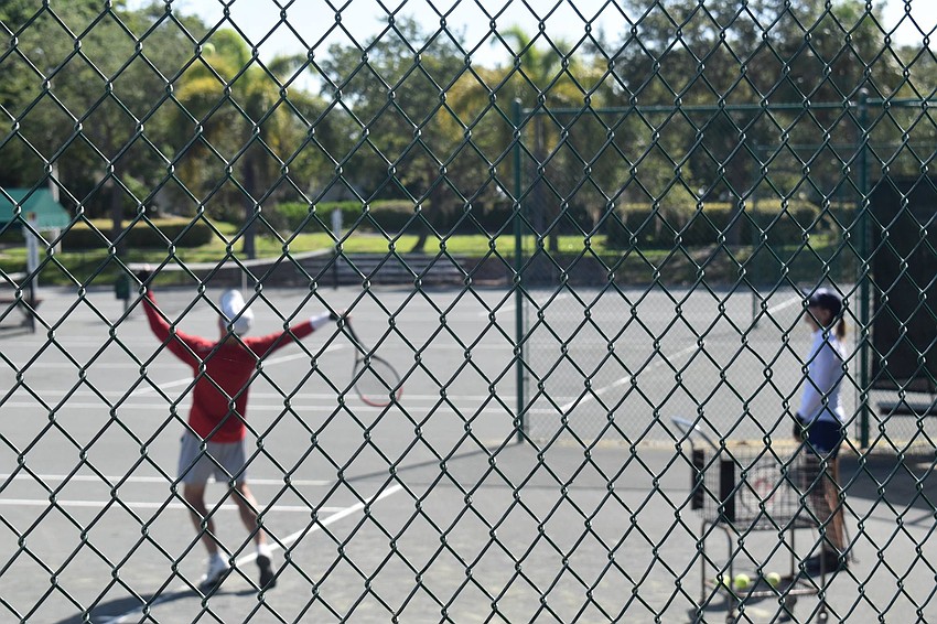 Skip Walters practices his serve as Kay Thayer looks on.