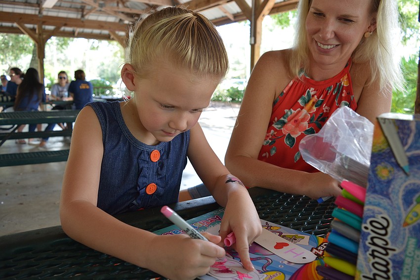 Four-year-old Olivia Zeller, with her mom, Jessica, makes her own book mark after eating a snow cone.