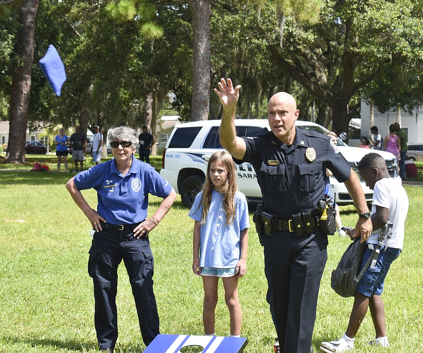 Demetri Konstantopoulos plays a game of cornhole with Joan Steber and Isabella Wiseman, 9.