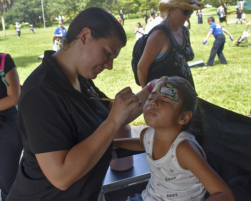 Gina Backhoff, of Childlike Productions, paints a unicorn on Leah Contreas', 5, face.