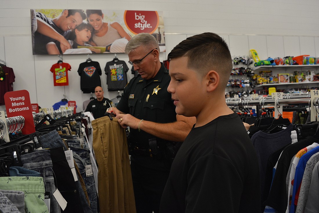 Manatee County Sheriff Rick Wells finds khaki pants for Carlos E. Haile Middle School student Ryan Gossett, 12, at Bealls Outlet.