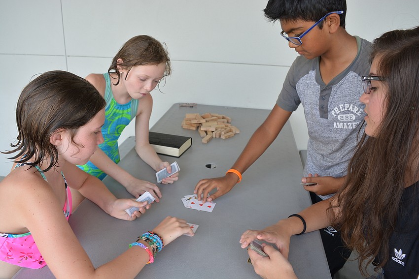 Clockwise from front left: campers Penelope Valentine, Juliana Bassler, Aayan Malik and Counselor-in-Training Victoria Kelley play a card game called ERS, with the goal of collecting as many cards as possible.