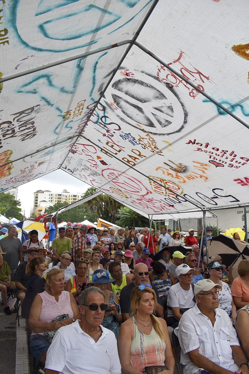 Woodstock Revival attendees hide from the rain to watch Kettle of Fish perform.