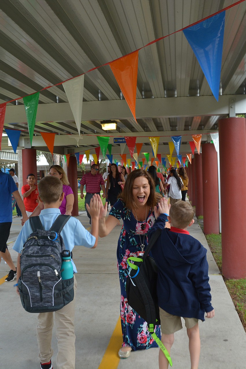 Braden River Elementary School fifth-grade teacher Katie McCollum gives students high fives as they walk to their classes as dance party music played. Photo by Pam Eubanks.