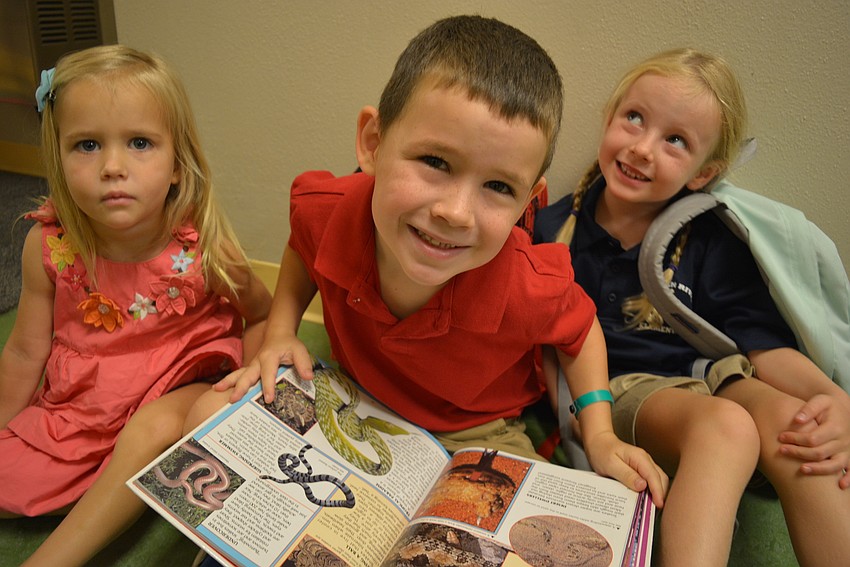 Three-year-old JoJo Hinton waits with her brother Jacob Hinton, 5, and friend, Penny Wells, 5, as they check out a book on snakes in the hallway before going into their kindergarten class at Braden River Elementary School.