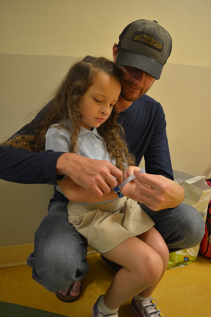 Five-year-old Jordan McCarte gets some snuggles and help with her wristband from her dad, Sean McCarte, before going into her kindergarten class at Braden River Elementary School. Photo by Pam Eubanks.