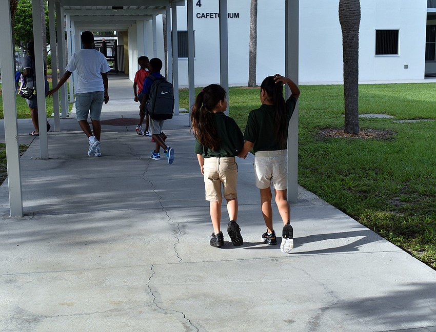 Two girls hold hands as they excitedly walk to class at Alta Vista Elementary. // Brynn Mechem
