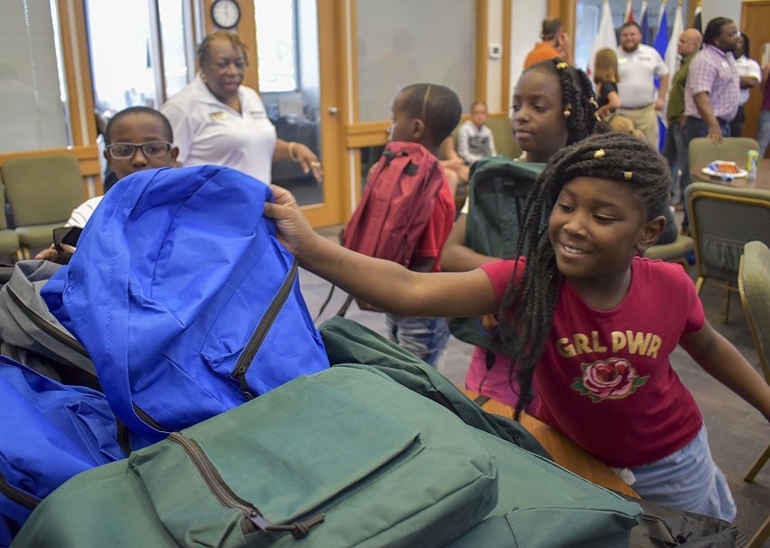 Tatiana Holloman, 7, picks out a blue backpack with Taliyah Wright, 9, Tj Steele, 8, and Cj Ford, 10.