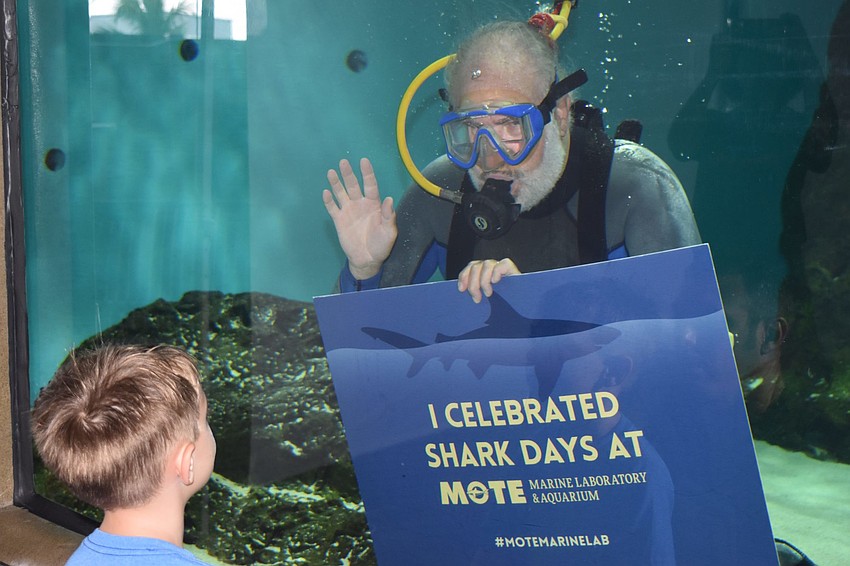 Colton White waves at diver Mark Fishman in the tank.