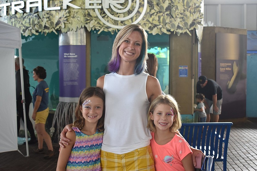 Sienna, Katie and Briella Tuttle pose in front of a shark tank.