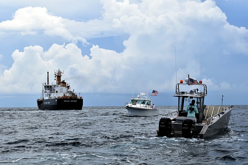 Several boats bearing U.S. flags circle the memorial site.