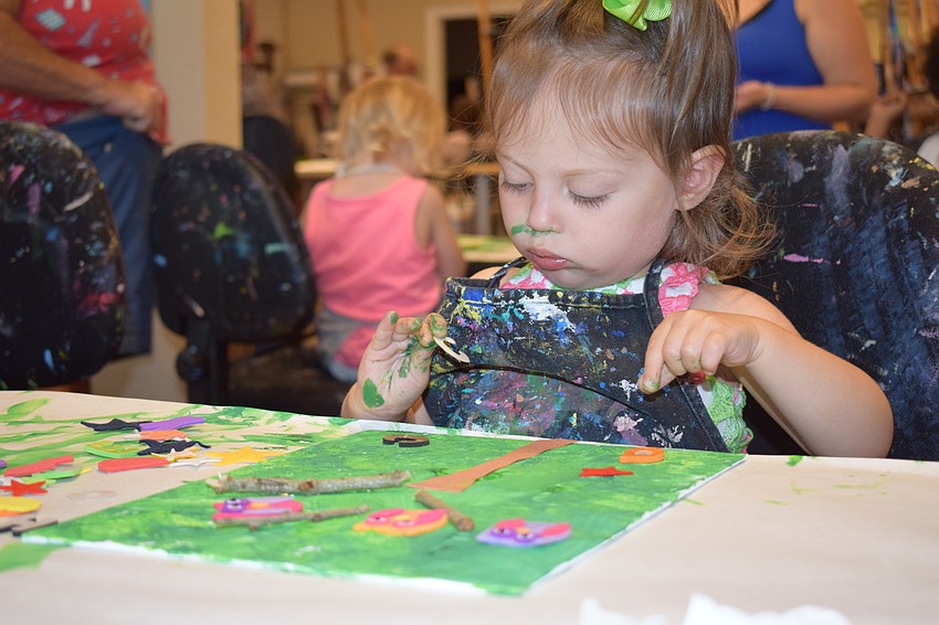 Palmetto 18-month-old Ryan Damico keeps adding to her painting.
