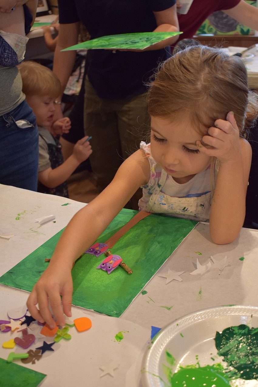 Sarasota 3-year-old Elena Collin thinks hard about what to put into her artwork next.