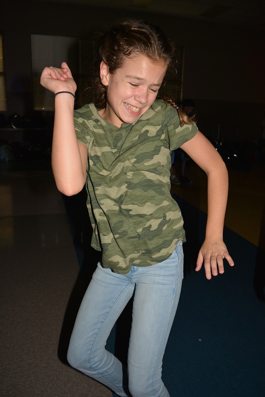 Sixth-grader Ava Collins bounds across the cafeteria to the song 