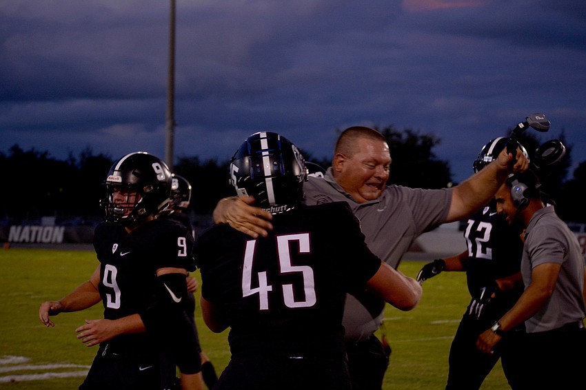 Pirates senior Luke Reeves hugs assistant coach Frank Post after Reeves intercepted a Largo pass.