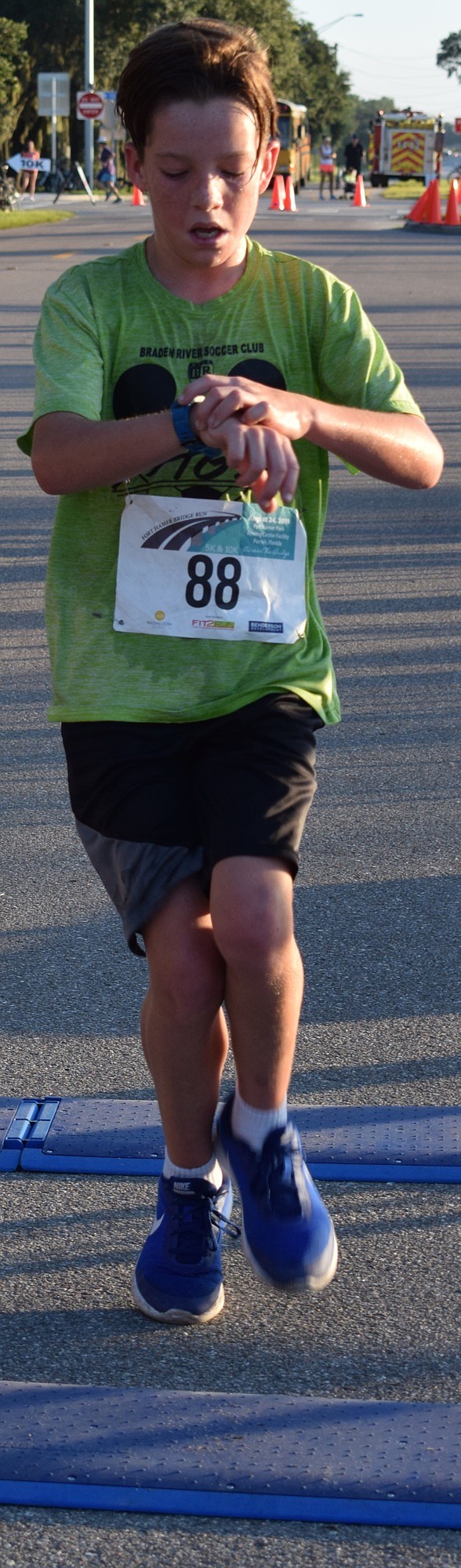 Bradenton resident Quinn Flammang checks his time as he completes his race at the Fort Hamer Bridge Run.