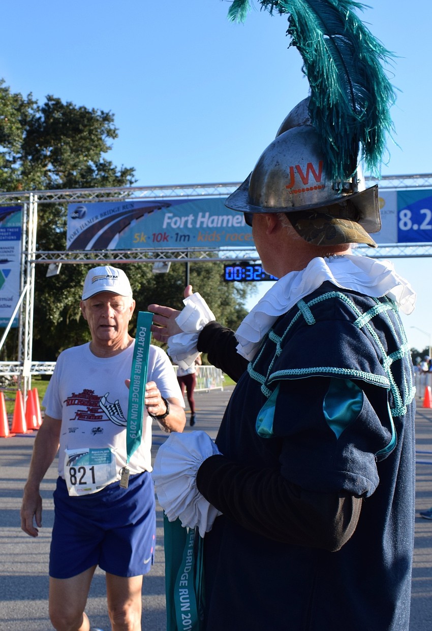 Crewe of Hernando De Soto member Cliff Hulsart, right, gives a medal to Bradenton resident Robert Schindler, left, after completing his race.