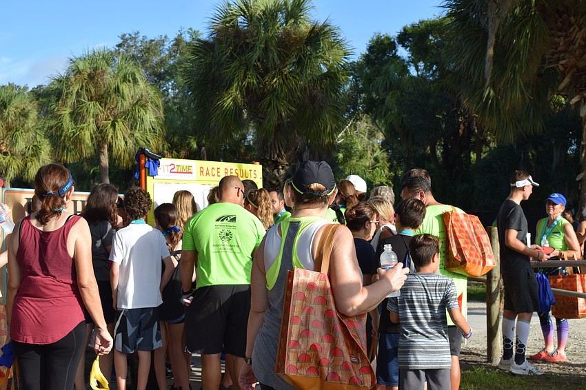 Dozens of people crowd around to look at race results after the Fort Hamer Bridge Run Saturday. More than 1,600 people participated in the third annual run.