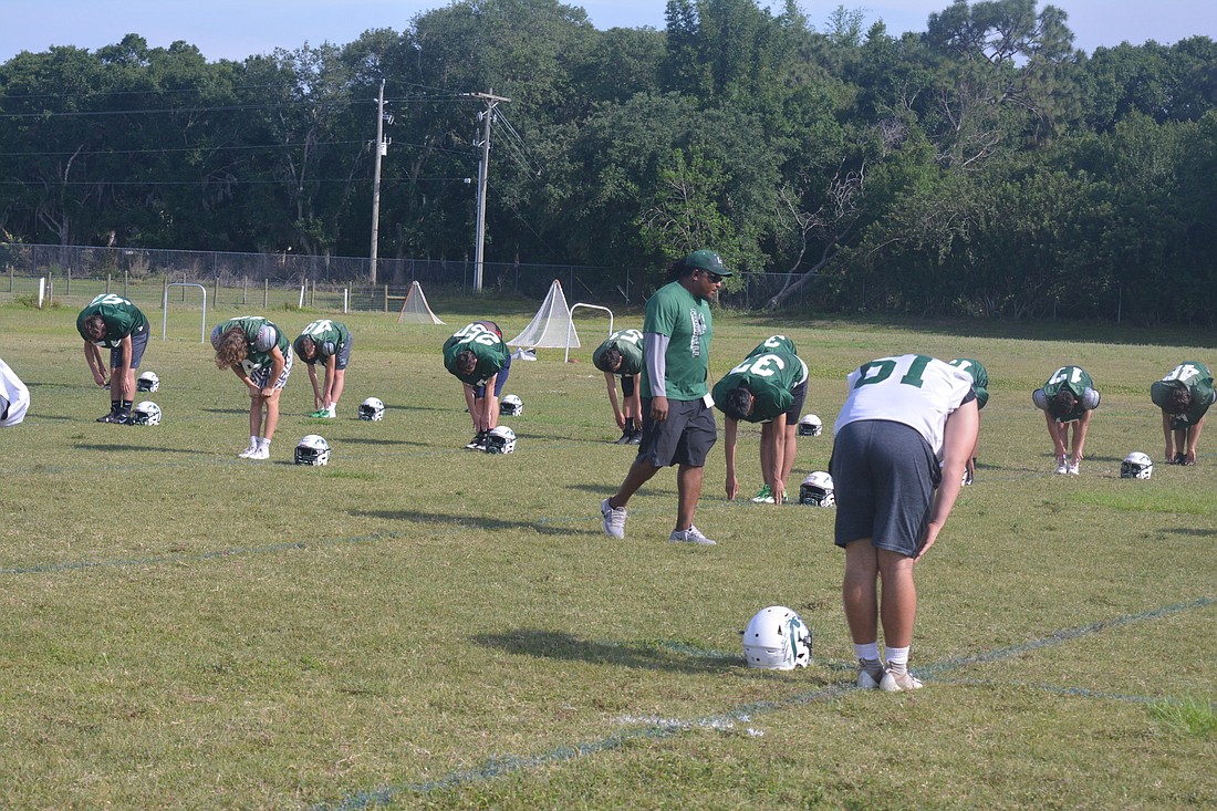 Lakewood Ranch coach Rashad West observes his team stretching during practice.  The Mustangs have not had many full practices this summer thanks to rainfall.