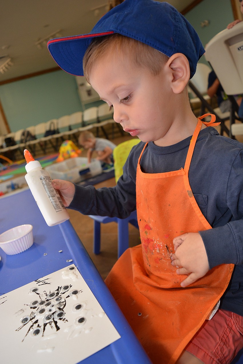 Two-year-old Maxwell Friedman, of River Club, piles on a little too much glue as he prepares to add eyes to the spider he made.