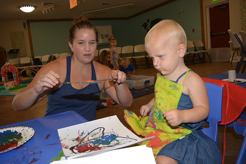 Edgewater resident Megan Martin and her 19-month-old daughter, Grace, use a fly swatter to   paint a picture of a fly.