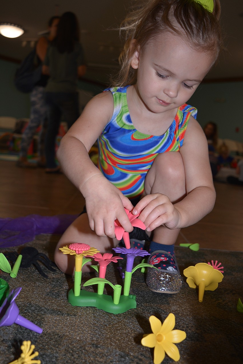 Three-year-old Bradenton resident Chevelle Egloff puts together flowers of her liking before  heading over to a bean bag toss game.
