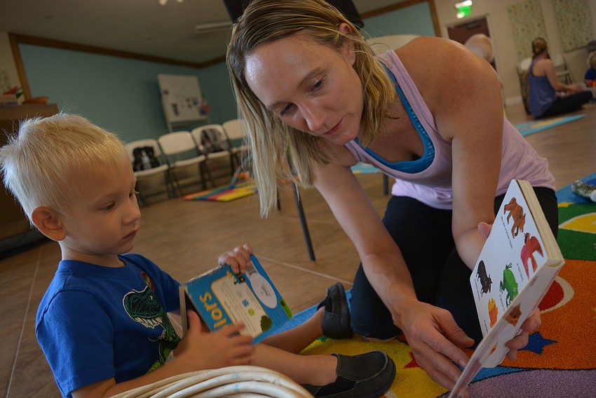 Two-year-old Zachary Ziskal, of Mill Creek, holds a book about cars while his mom, Stephanie Ziskal, reads 