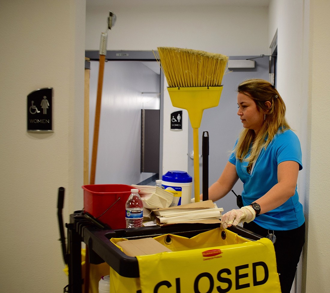Manatee Technical College custodian Claudia Estrada Carmona works on cleaning a women&#39;s bathroom during her night shift. During the day, she freelances as a web developer.
