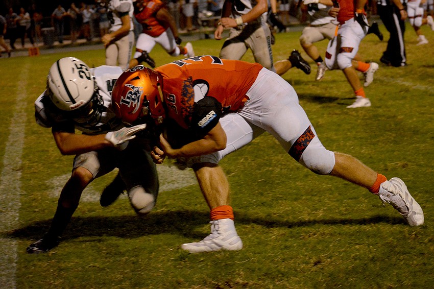 Lakewood Ranch senior Jake Zapatha (25) lays a hit on Lemon Bay running back Aidan Moore.