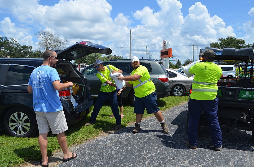 Sarasota County workers help resident Brian Miller pack sandbags into his car.