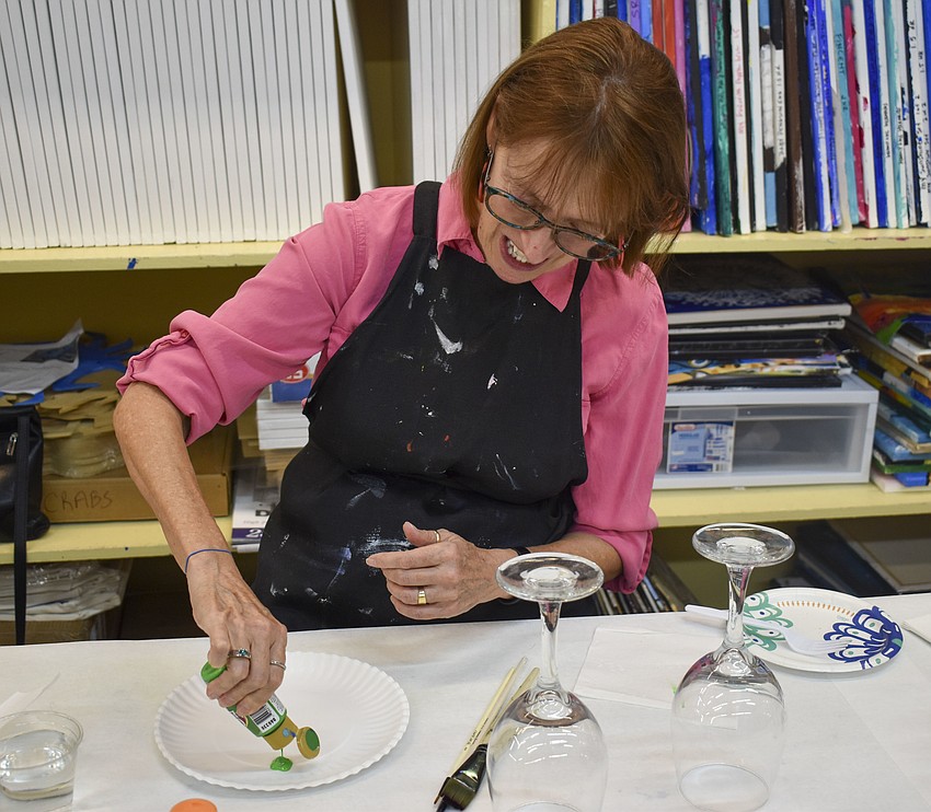 Barbara Scissors adds paint to her plate to get ready for her wine glass.