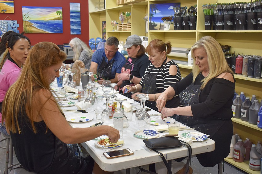 The attendees who chose to paint wine glasses begin to add paint to their plates.