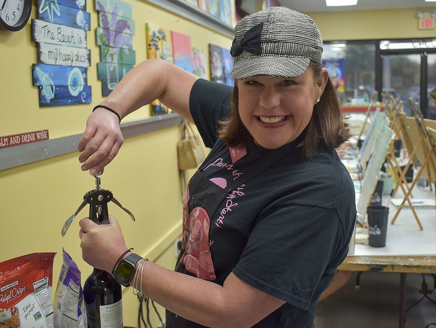 Shon Ewens, executive director of Healthy Start Sarasota, uncorks a bottle of wine.