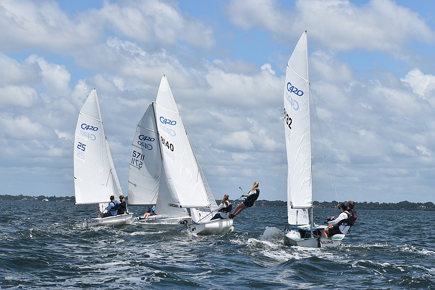 Sailors lean out to tack.