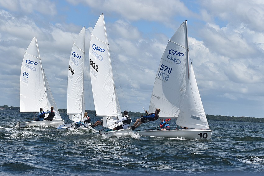 A group of 420 sailboats gather near their starting line.