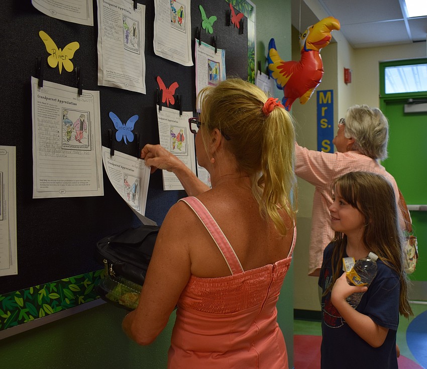 Braden River Elementary School second-grader Annie Schroeder, 7, center, shows her grandmothers Debbie Bretoi, front, and Sandy Rose, back, assignments she worked on in class that are hanging on a board in the hallway.