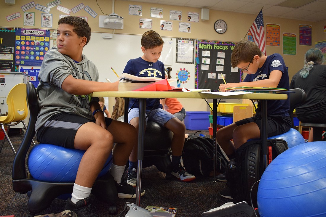 From left, Gilbert W. McNeal Elementary School fifth-graders Bakari Simmons, Harrison Phillips and Isaiah Buckson, work on an essay during class while sitting on exercise balls.