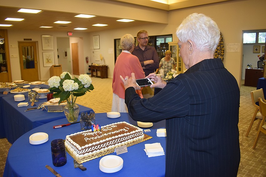 Lillian Sands takes a photo of the anniversary cake.