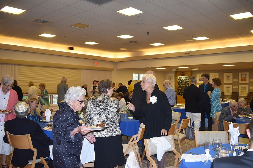 People navigate the room with full plates.