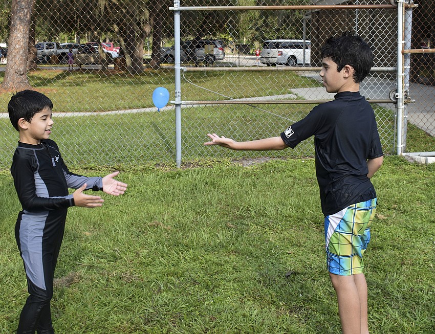 Dave Oleaga throws a water balloon to his little brother, Josh.