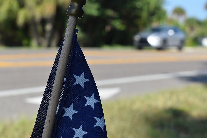 Cars speed past, causing the flags to fly.