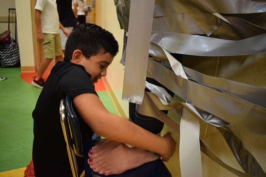 Braden River Elementary School third-grader Elias Nehme, 8, tapes Assistant Principal Krista Francies ankles together.
