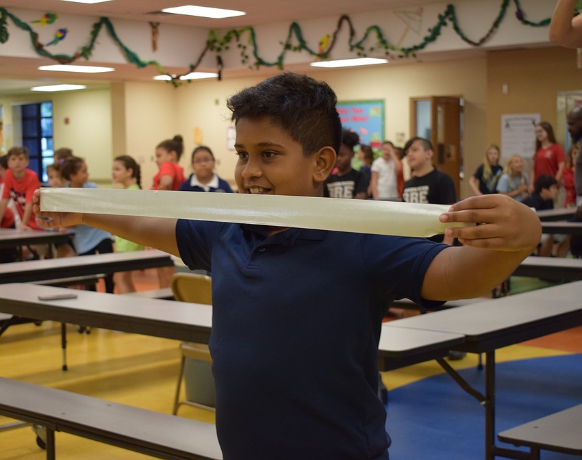Braden River Elementary School fourth-grader Roshan Leonardo, 9, stretches out his piece of tape before placing it on Assistant Principal Krista Francies.
