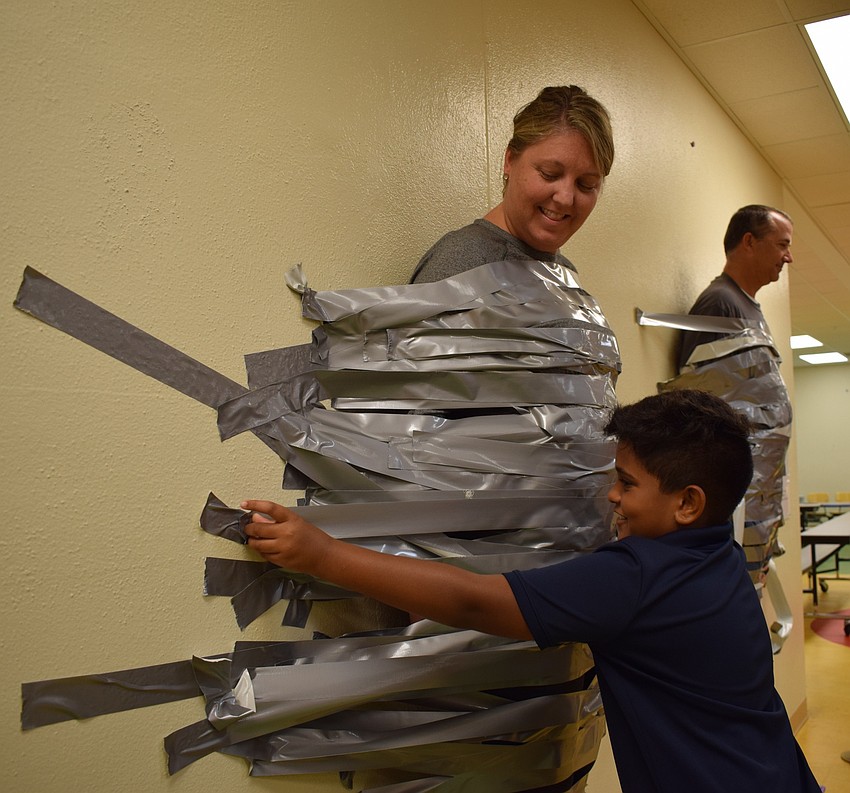 Braden River Elementary School fourth-grader Roshan Leonardo, 9, right, places a strip of tape across Assistant Principal Krista Francies.