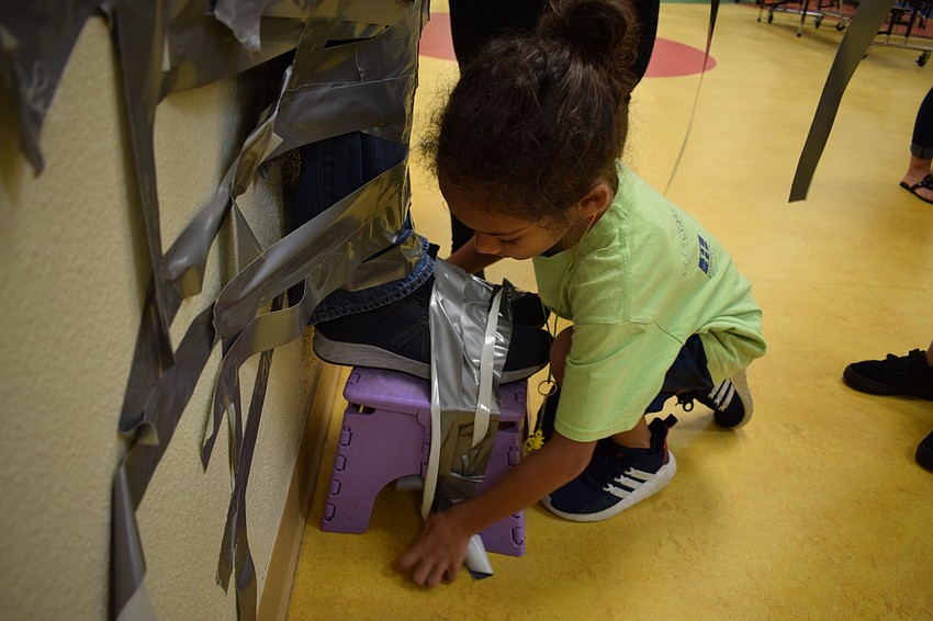 Braden River Elementary School second-grader Maliek Burchell, 7, tapes Principal Joshua Bennett's feet to a stool. Burchell then said, 